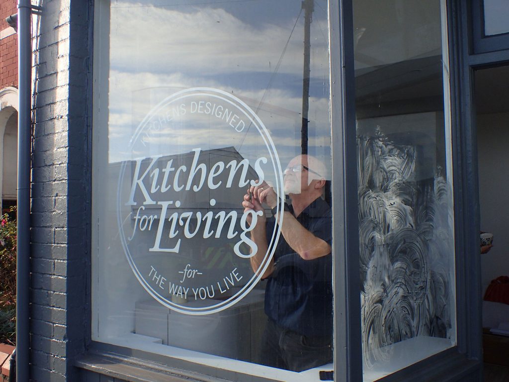 Man installing vinyl sticker in shop window